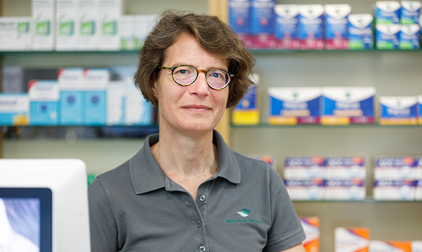 Apothekerin der Trierweiler Apotheke steht vor einem Medikamentenregal.