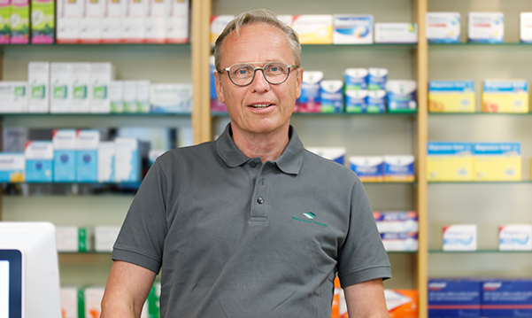 Apotheker der Trierweiler Apotheke steht vor einem Medikamentenregal.