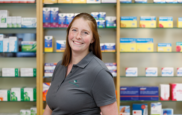 Apothekerin der Trierweiler Apotheke steht vor einem Medikamentenregal.
