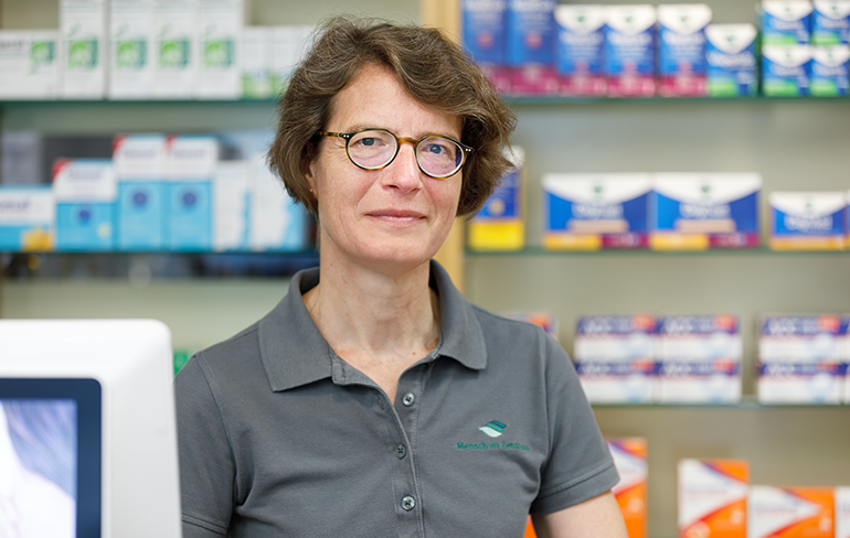 Apothekerin der Trierweiler Apotheke steht vor einem Medikamentenregal.