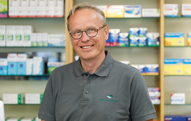 Apotheker der Trierweiler Apotheke steht vor einem Medikamentenregal.