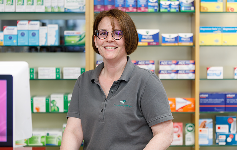 Apothekerin der Trierweiler Apotheke steht vor dem Medikamentenregal.