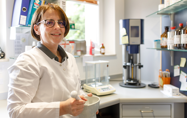 Apothekerin der Trierweiler Apotheke steht im Labor und mischt in einer Schale eine Rezeptur.