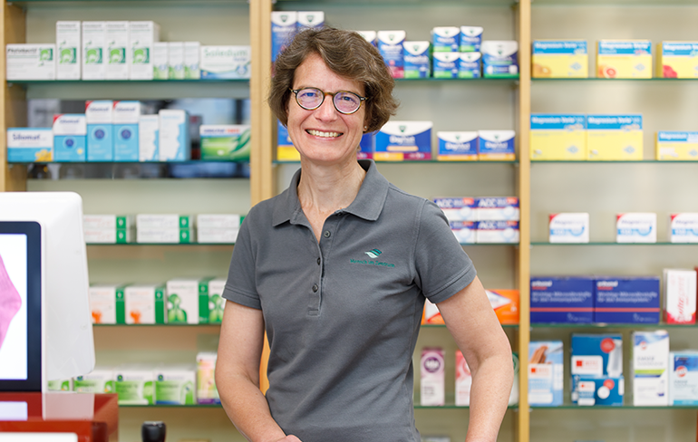 Apothekerin der Trierweiler Apotheke steht vor dem Medikamentenregal.