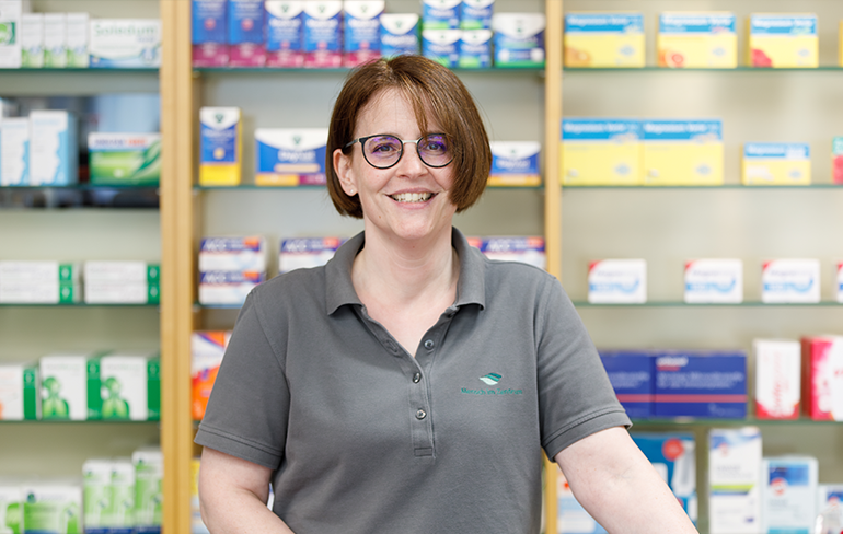 Apothekerin der Trierweiler Apotheke steht vor dem Medikamentenregal.