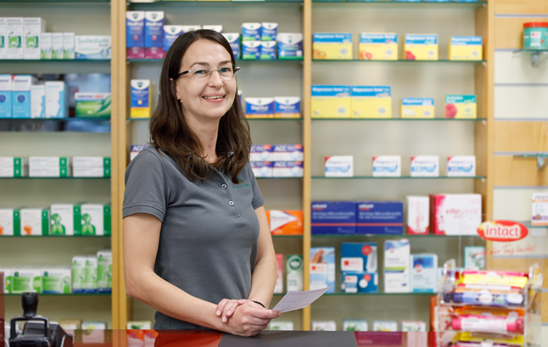 Apothekerin der Trierweiler Apotheke steht vor dem Medikamentenregal.