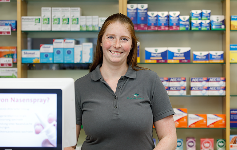Apothekerin der Trierweiler Apotheke steht vor dem Medikamentenregal.