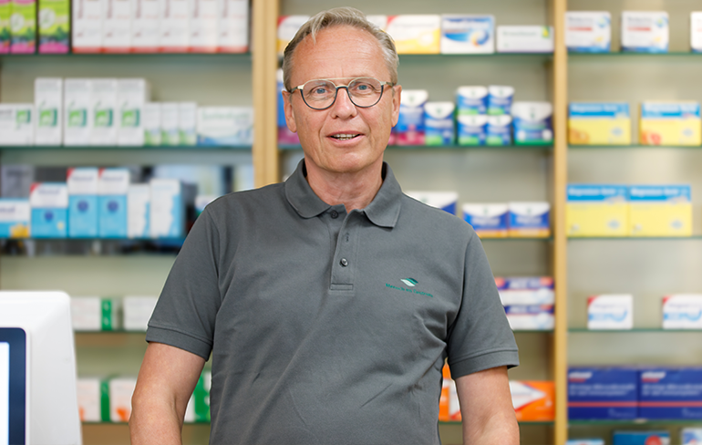 Apotheker der Trierweiler Apotheke steht vor dem Medikamentenregal.