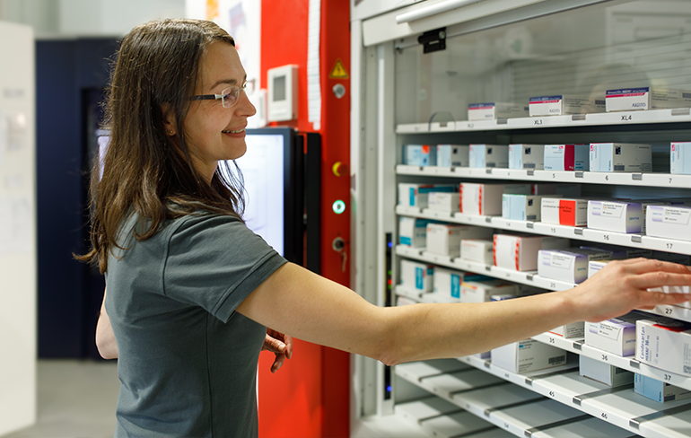 Apothekerin der Trierweiler Apotheke in Trierweiler steht vor dem Medikamentenregal.