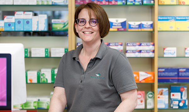 Fröhliche Mitarbeiterin der Trierweiler Apotheke Trierweiler steht im Labor mit Medizinprodukten in der Hand.